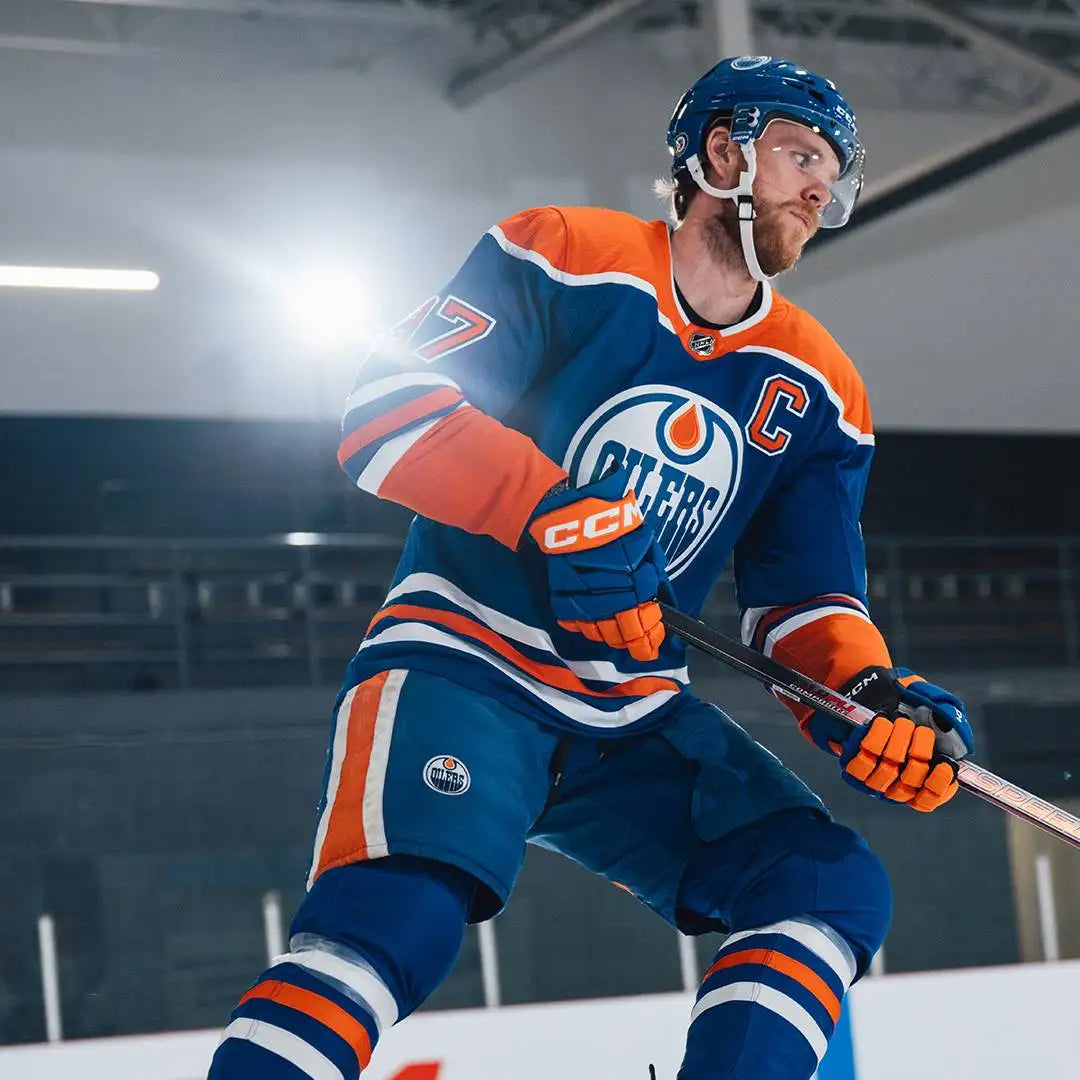 Blue and orange edmonton oilers hockey jersey with white trim, featuring the team logo and captain’s ’c’ on the chest.