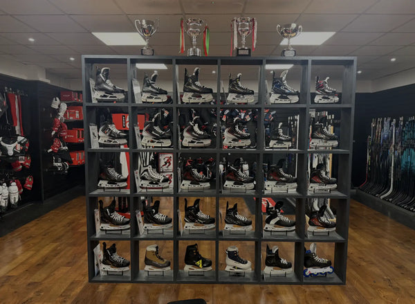 Black and white hockey skates displayed in a grid of shelves.