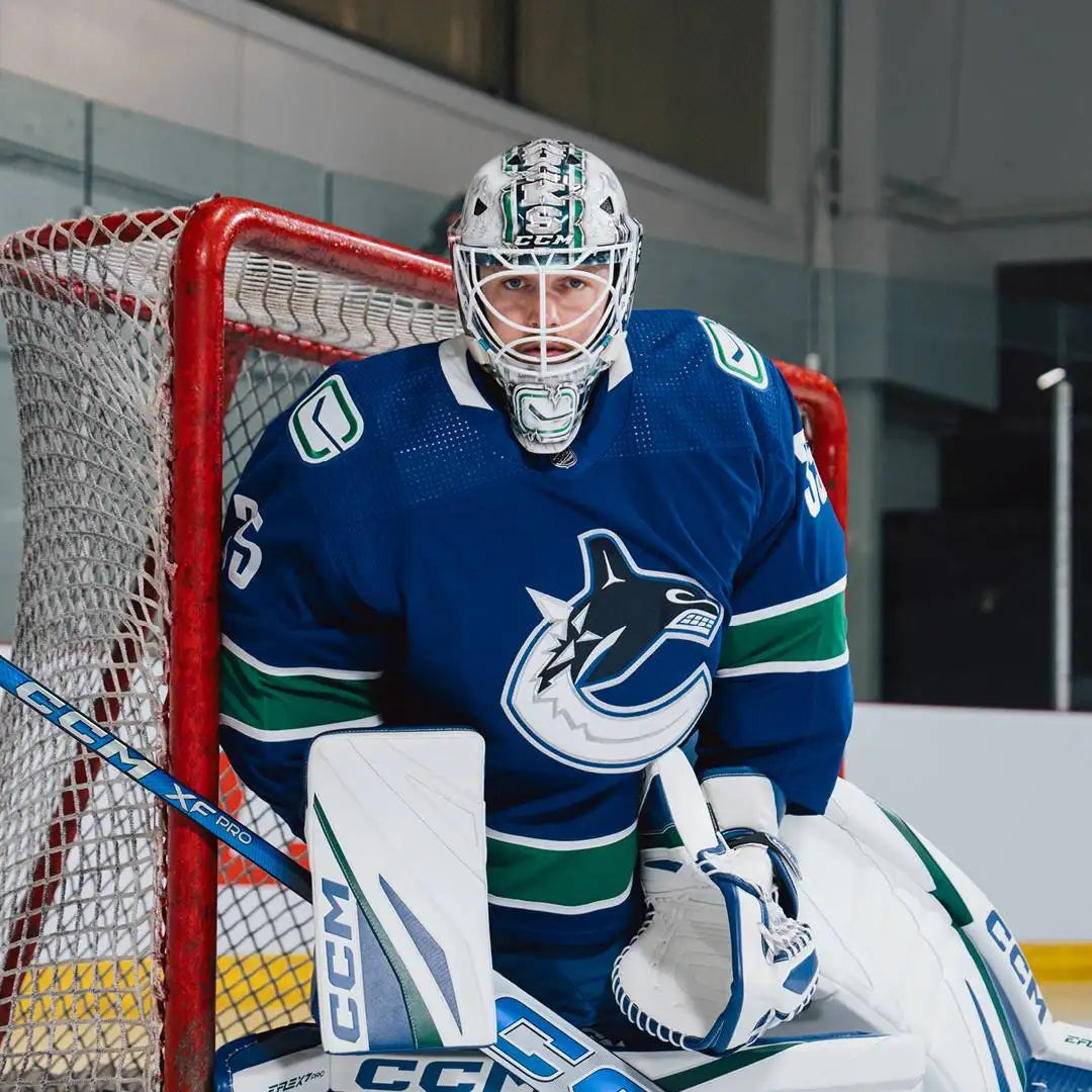 Blue and green vancouver canucks hockey goalie jersey with white accents, featuring the team’s orca logo on the chest.