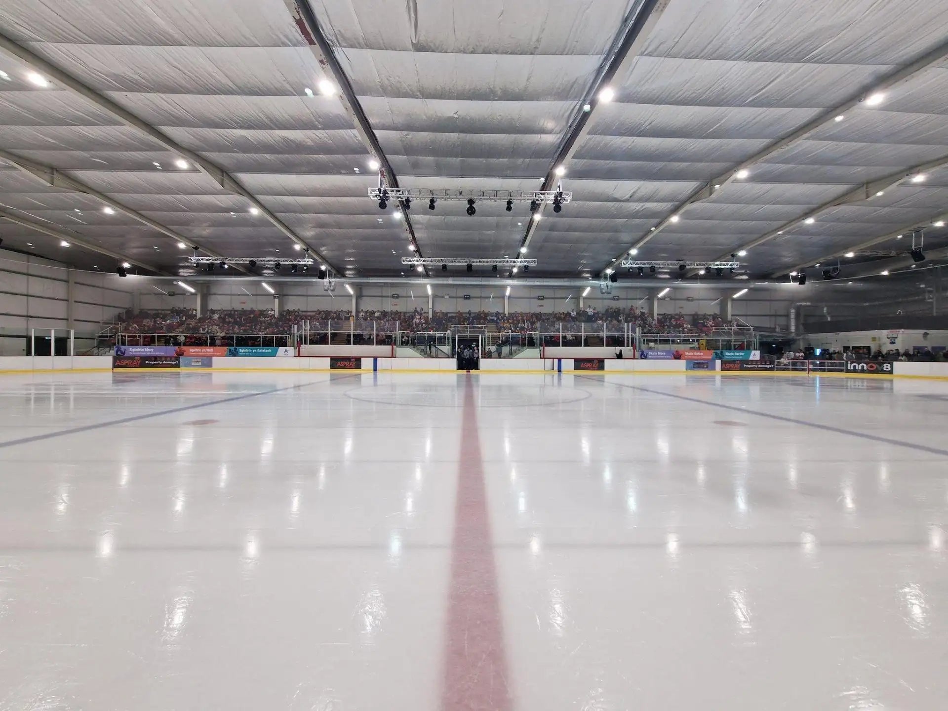 The ice rink features a smooth, glossy white surface with a central red line marking the center of play.