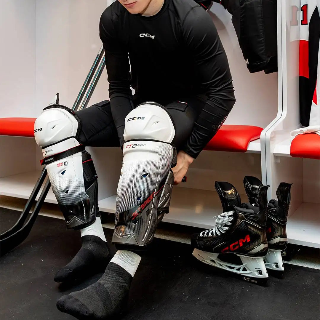 White and black ccm ft8 pro hockey knee pads with a mesh design.